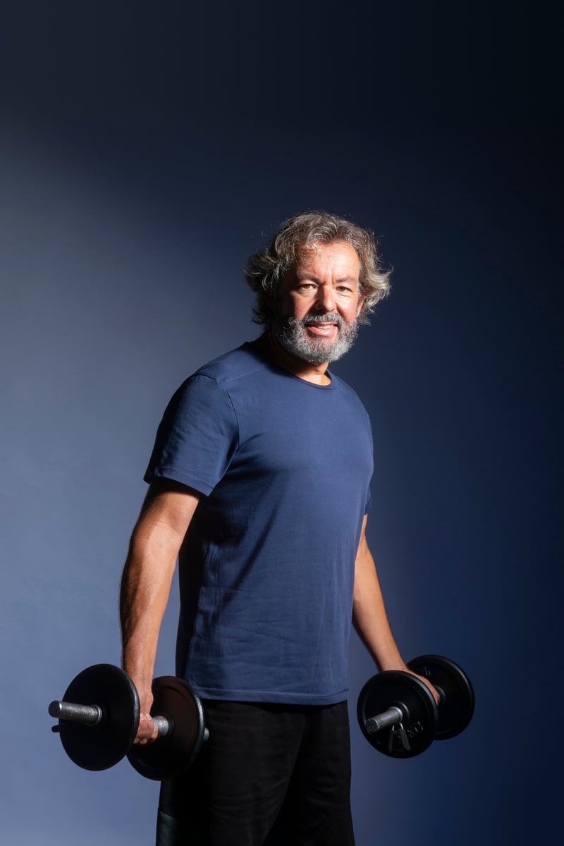 Grey haired man doing weight training. Senior fitness. Smiling man.